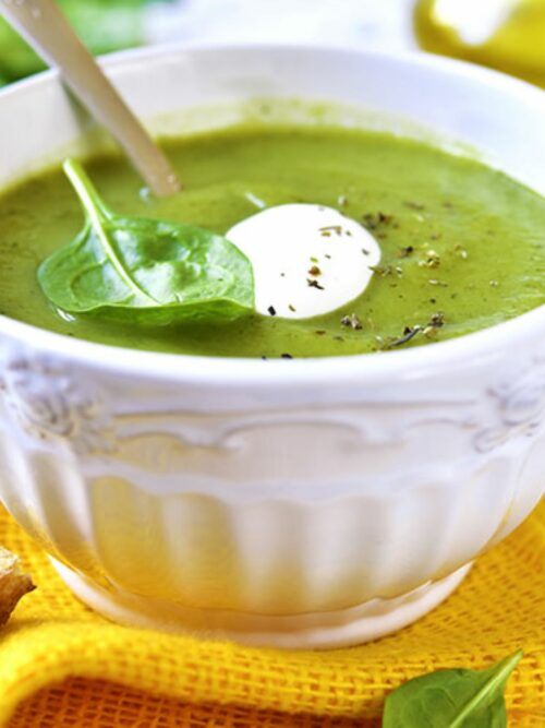 Brokkoli-Spinat-Suppe wird dekoriert mit Brokkoli in einer weißen Schale serviert