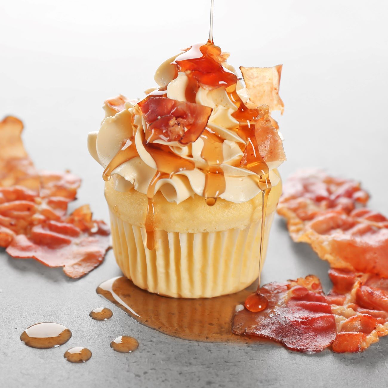 Bacon-Cupcakes mit Frischkäse-Frosting werden nah und frontal gezeigt.