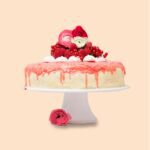 Erdbeer-Drip-Cake wird verziert auf einer Kuchenplatte serviert.