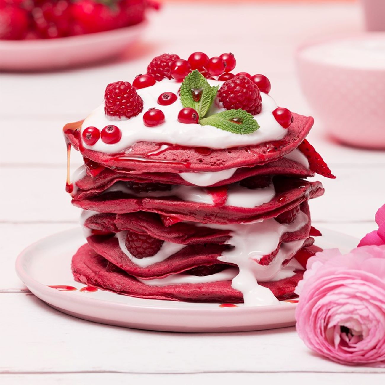 Red Velvet Pancakes werden mit Toppin auf einem weißen Teller mit Deko präsentiert