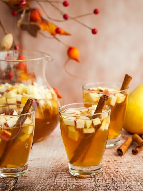 Apfel-Birnen-Punsch wird mit Zimtstangen in Gläsern serviert.