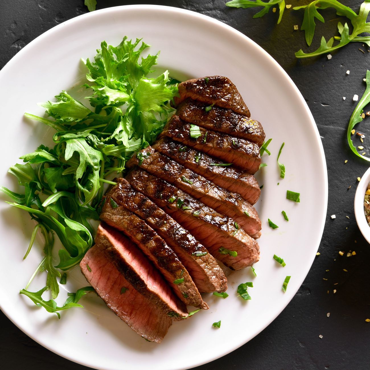 Steak aus der Heißluftfritteuse wird angeschnitten von oben mit Salat gezeigt.