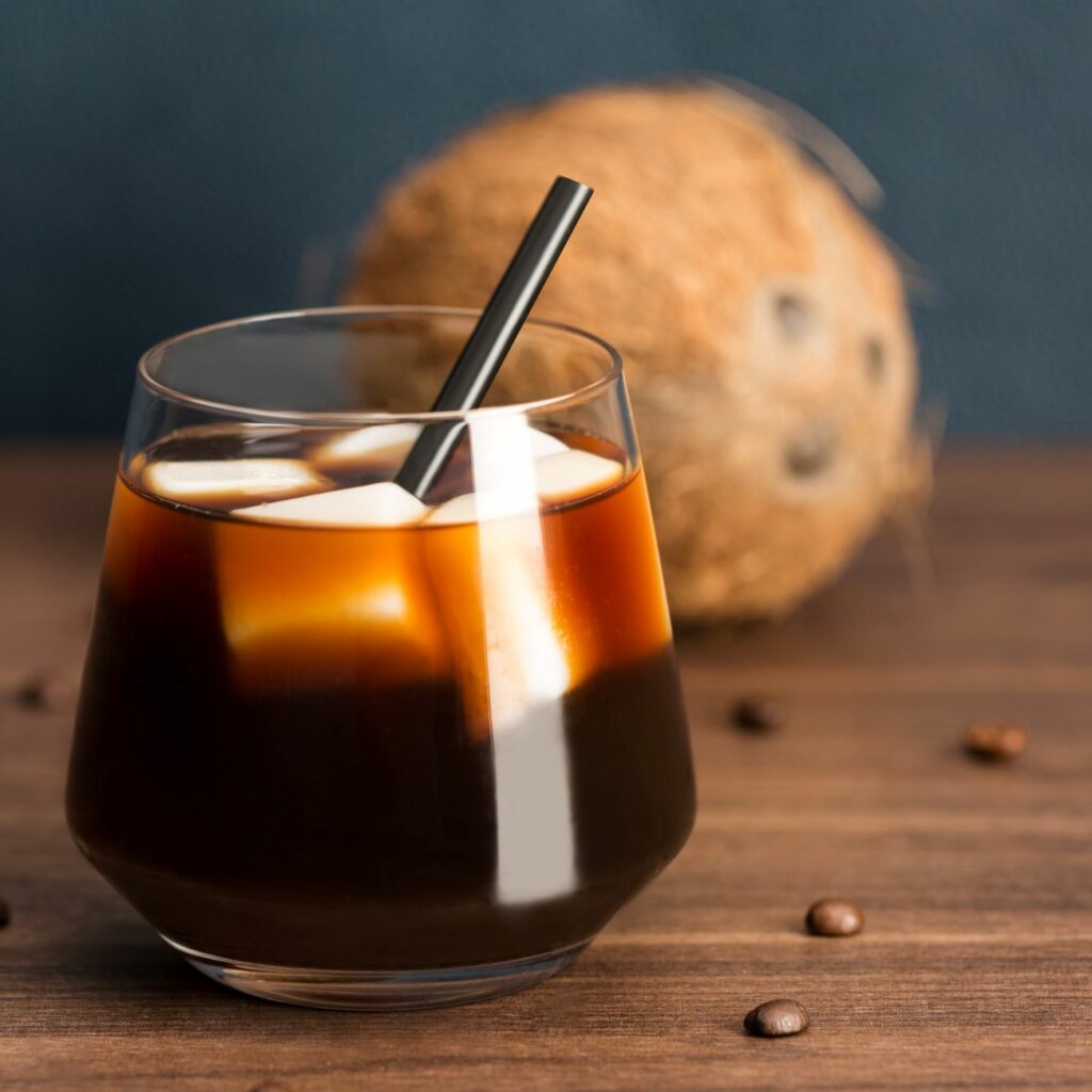 Coffee on Ice z ledenimi kockami kokosovega mleka postrežemo v kozarcu s slamico.