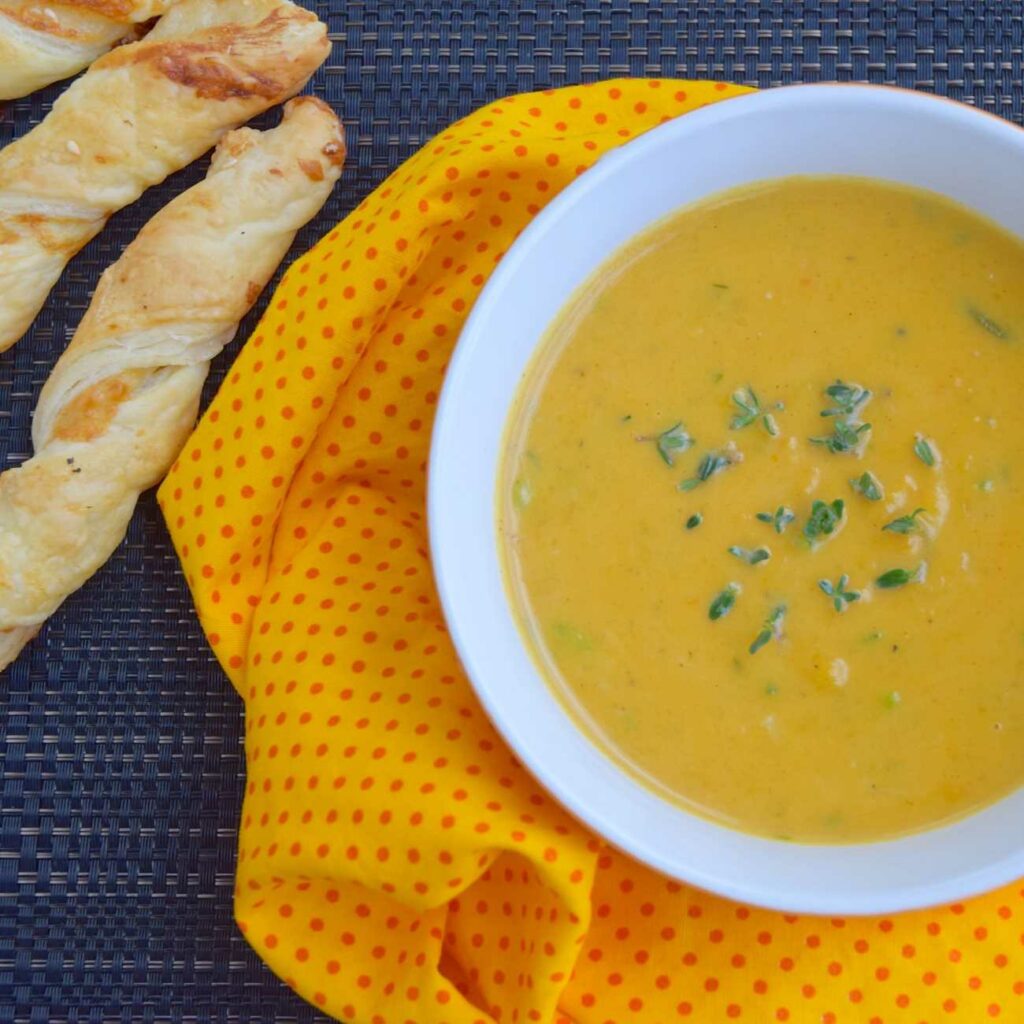 Krompirjeva curry juha se postreže z zelišči na krpi s kruhovimi palčkami.