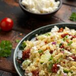 Couscous Salat wird in einem Teller auf einem Holztisch serviert.