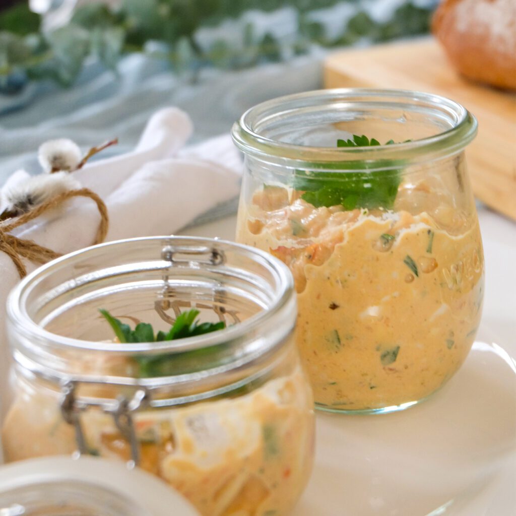 Eiersalat wird in zwei kleinen Gläsern mit Petersilie garniert präsentiert.