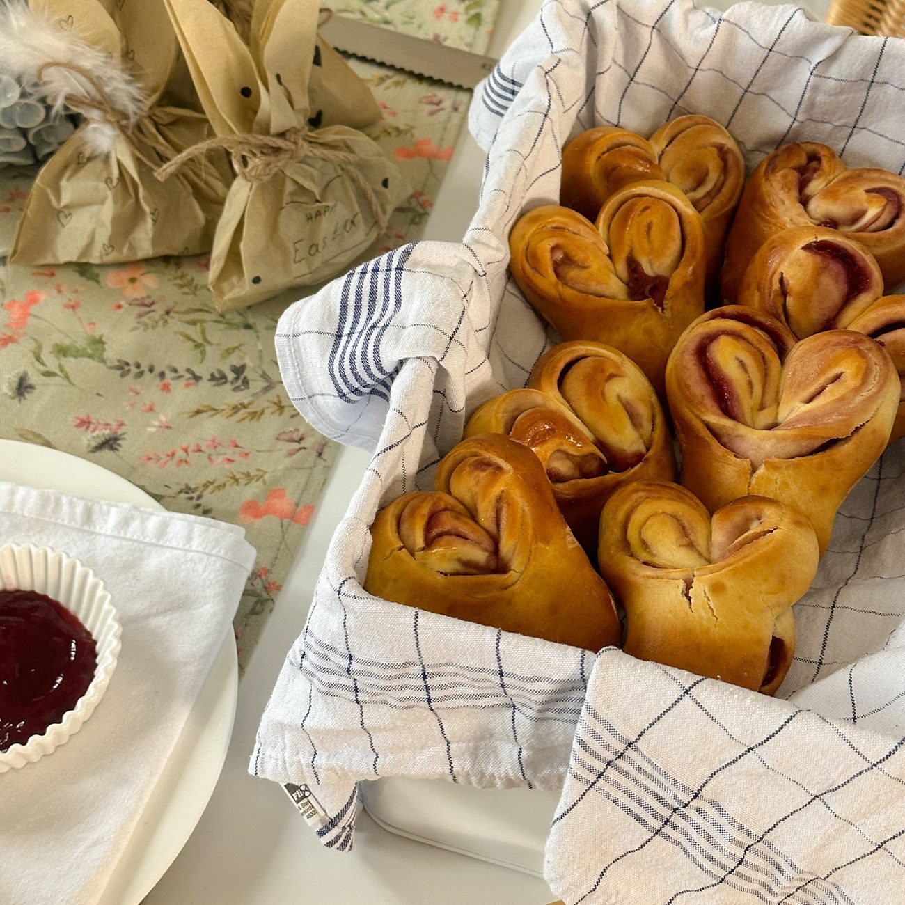Osterhasen aus Hefeteig werden in einem Brotkorb mit Geschirrtuch auf einem Ostertisch präsentiert.