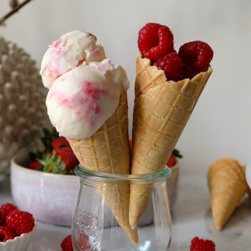 Malinová jogurtová zmrzlina je zobrazená v kornútku na zmrzlinu.