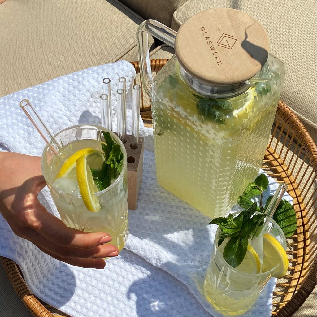 Limonade wird in einer Karaffe und zwei Gläsern draußen in der Sonne gezeigt.
