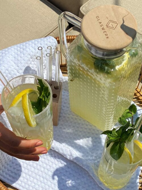 Limonade wird in einer Karaffe und zwei Gläsern draußen in der Sonne gezeigt.