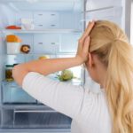 Geruch im Kühlschrank: Frau steht ratlos vor ihrem Kühlschrank.