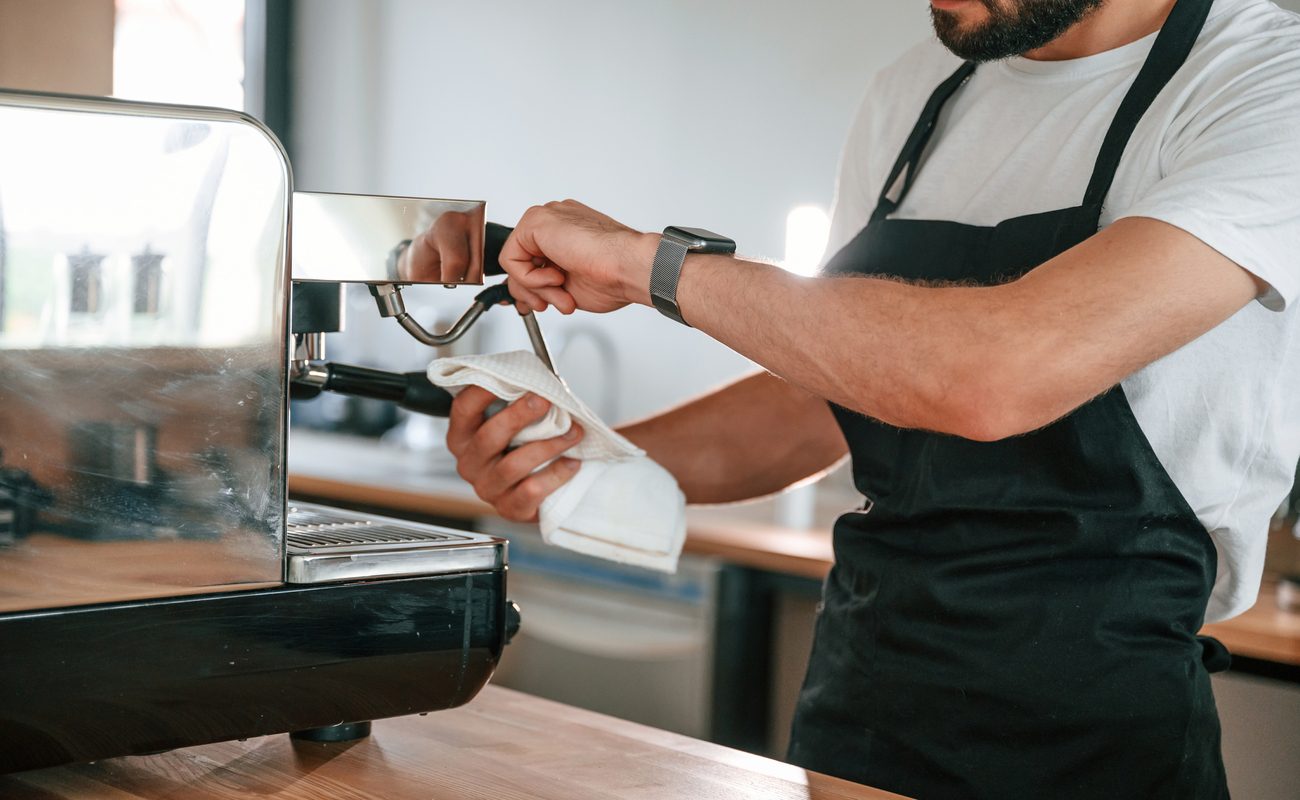 Kaffeemaschine reinigen: Junger Mann reinigt eine Kaffeemaschine